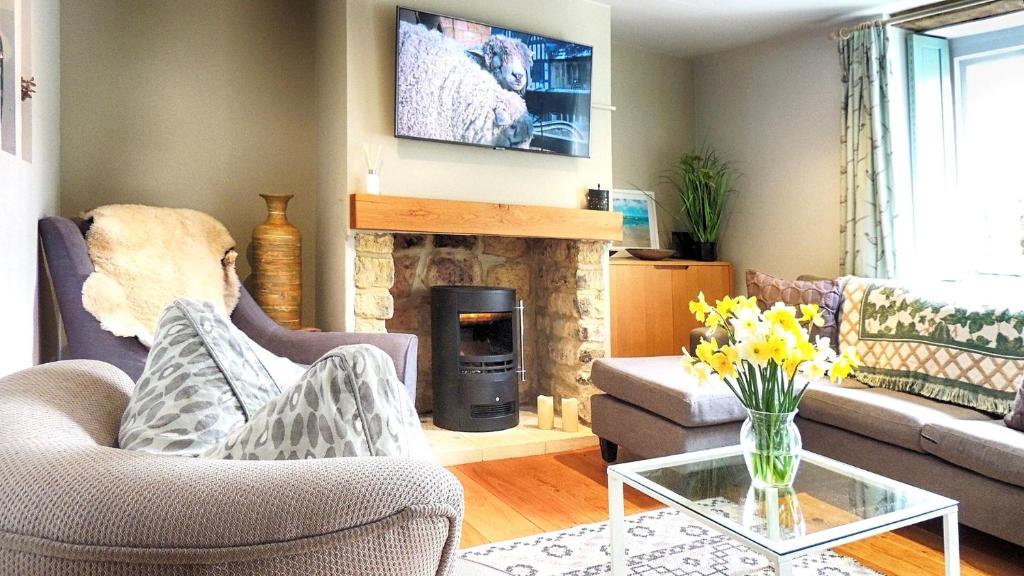a living room with a couch and a fireplace at Woodbine Cottage in Bourton on the Water