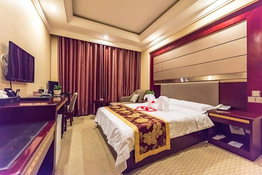 a hotel room with a large bed and a desk at Dunhuang Gold Dragon Hotel in Dunhuang