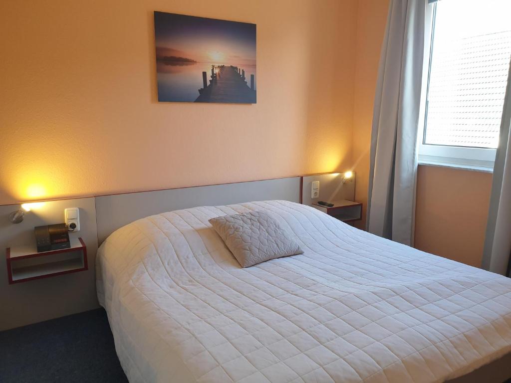 ein Schlafzimmer mit einem weißen Bett mit einem Bild an der Wand in der Unterkunft Fewo Panorama 14 in Laboe