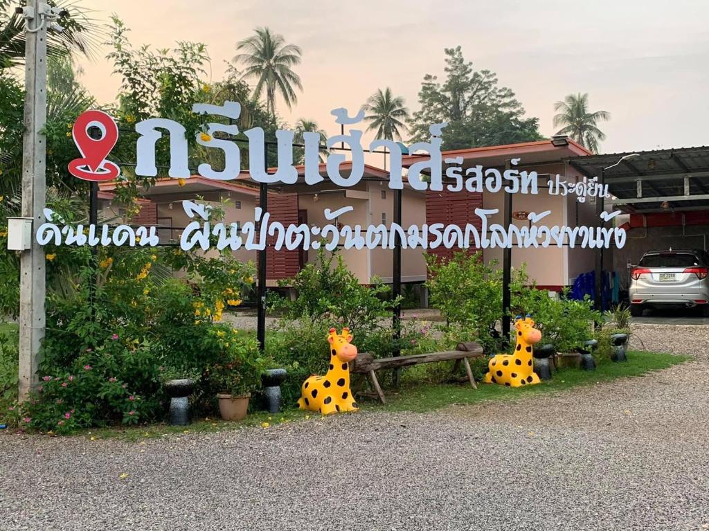 um sinal com duas girafas em frente a um edifício em Green House Resort Praduyuen em Uthai Thani