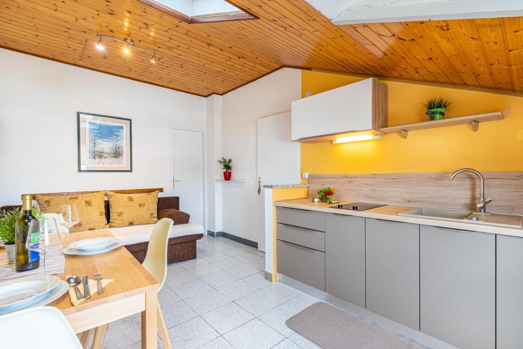 a kitchen with white cabinets and a table and a couch at Apartments Alida in Poreč