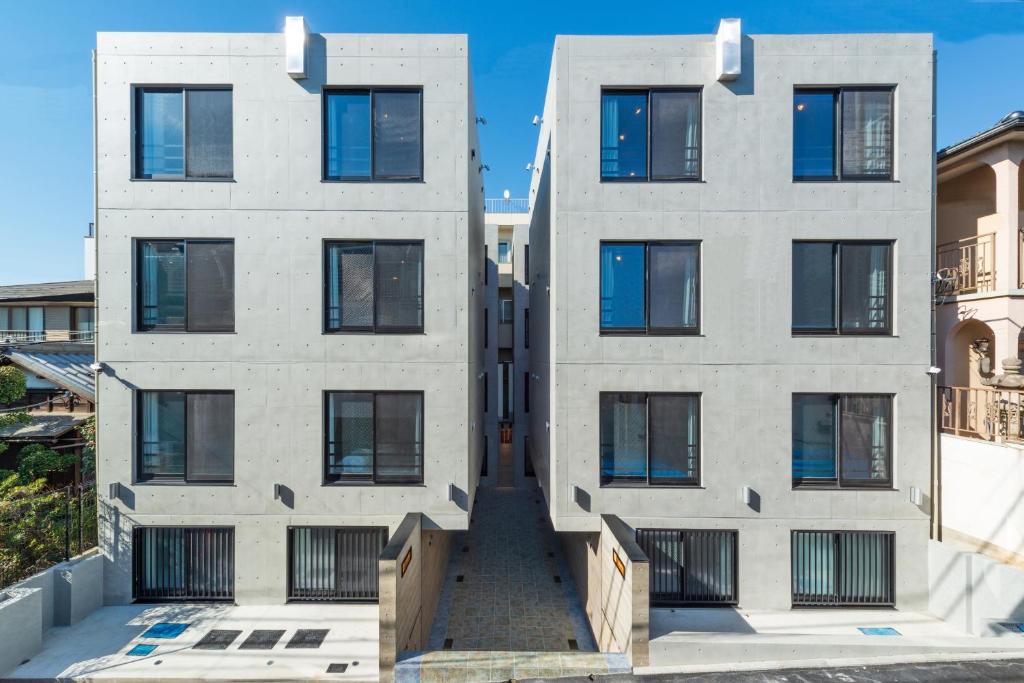 - une vue extérieure sur un bâtiment blanc doté de fenêtres noires dans l'établissement Luana Shibuya, à Tokyo