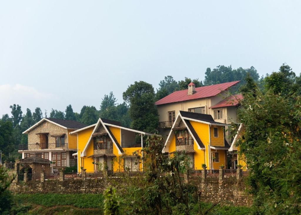 a group of houses in a field with a fence at The Naturewalk in Mukteswar