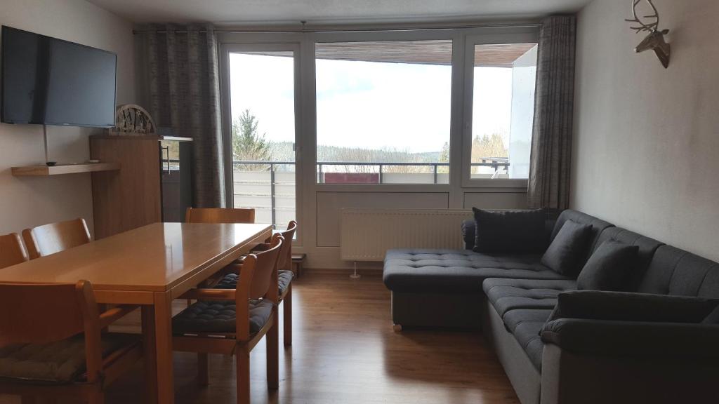 a living room with a couch and a table and a couch and a dining room at Ferienwohnung mit extra Schlafzimmer und Blick in den Bayrischen Wald oberhalb von Sankt Engelmar in Sankt Englmar
