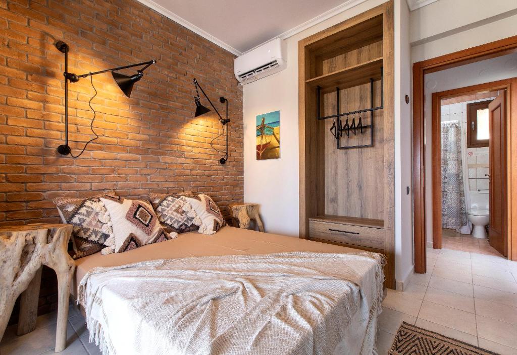 a bedroom with a bed and a brick wall at Porto Thea Alexandra Shared Pool Villa, Afytos in Afitos