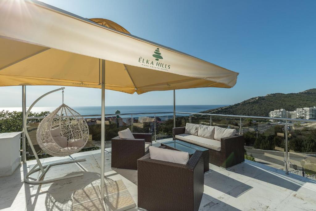 a patio with a large umbrella and chairs and the ocean at Elka Hills Hotel in Sukko