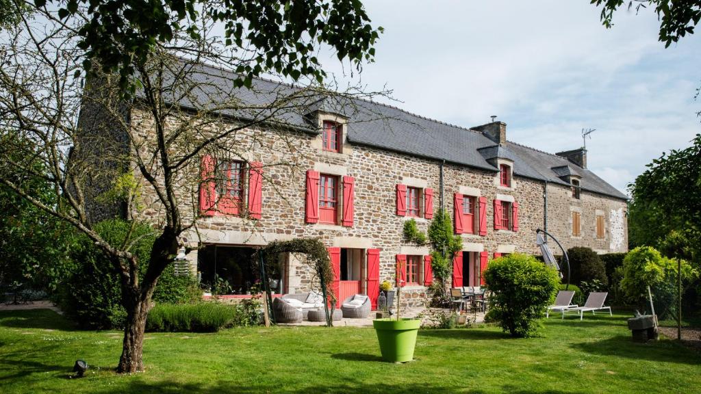 un grand bâtiment en briques avec volets rouges dans l'établissement Au Jardin D'Eloïse, à Tréméreuc