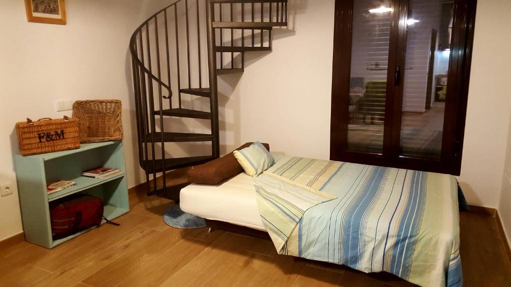 a bedroom with a bed and a spiral staircase at El Loft de Dulcinea: en el corazón de El Toboso. in El Toboso