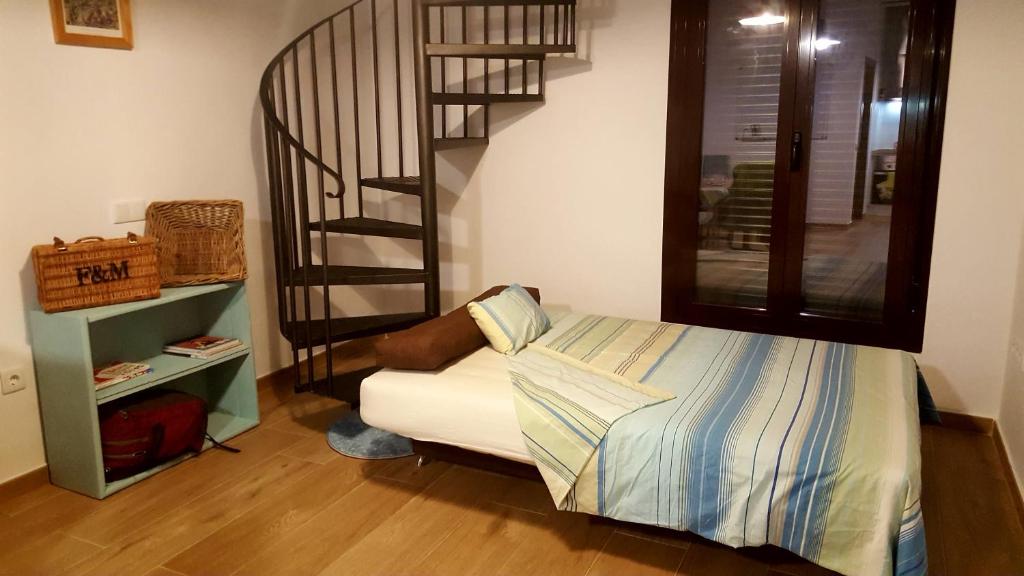 une chambre avec un lit et un escalier en colimaçon dans l'établissement El Loft de Dulcinea: en el corazón de El Toboso., à El Toboso