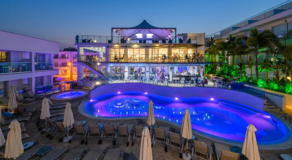 Tasia Maris Oasis في أيا نابا: مسبح الفندق مع الكراسي والمظلات في الليل