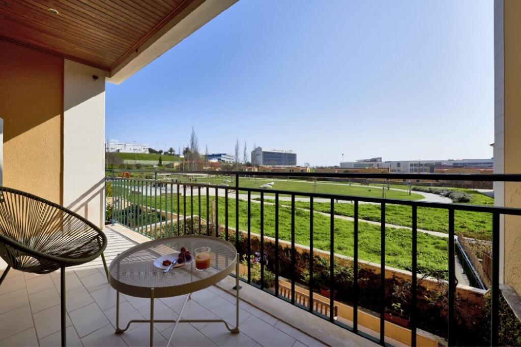 einen Balkon mit einem Tisch und Blick auf ein Feld in der Unterkunft Carcavelos Apartment in Carcavelos