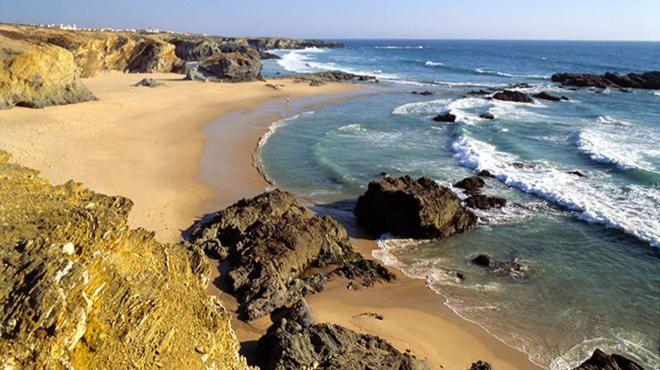 a beach with rocks and the water and the ocean w obiekcie Casa São Francisco w mieście Porto Covo