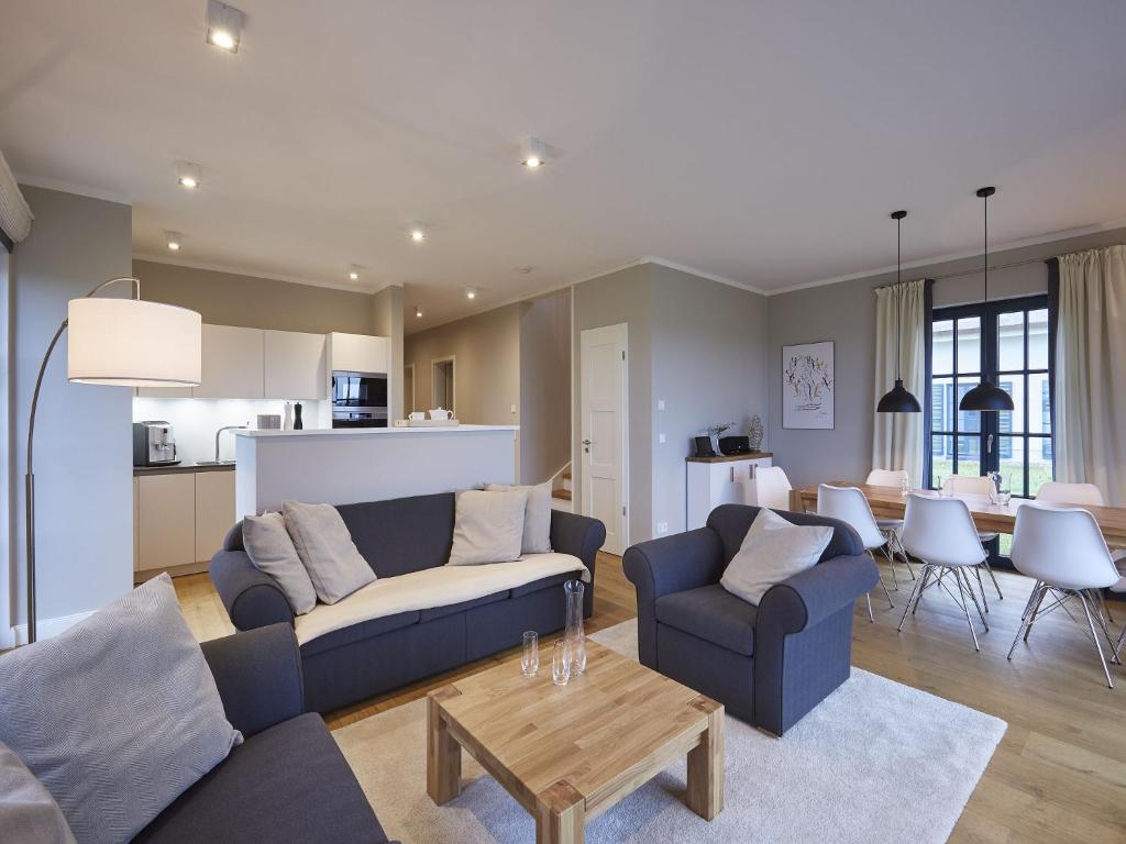 a living room with a couch and a table at Reetland am Meer - Luxus Reetdachvilla mit 3 Schlafzimmern, Sauna und Kamin F11 in Dranske