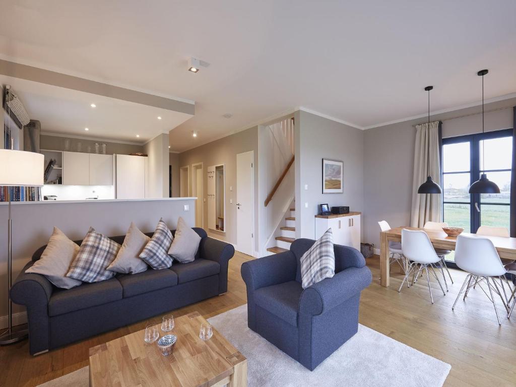 a living room with a blue couch and a table at Reetland am Meer - Premium Reetdachvilla mit 3 Schlafzimmern, Sauna und Kamin F10 in Dranske
