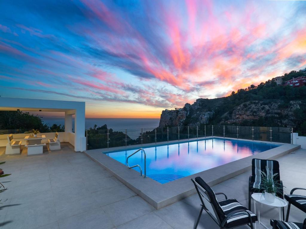 a swimming pool with a sunset in the background at Holiday Home Vista al Mar by Interhome in Benitachell