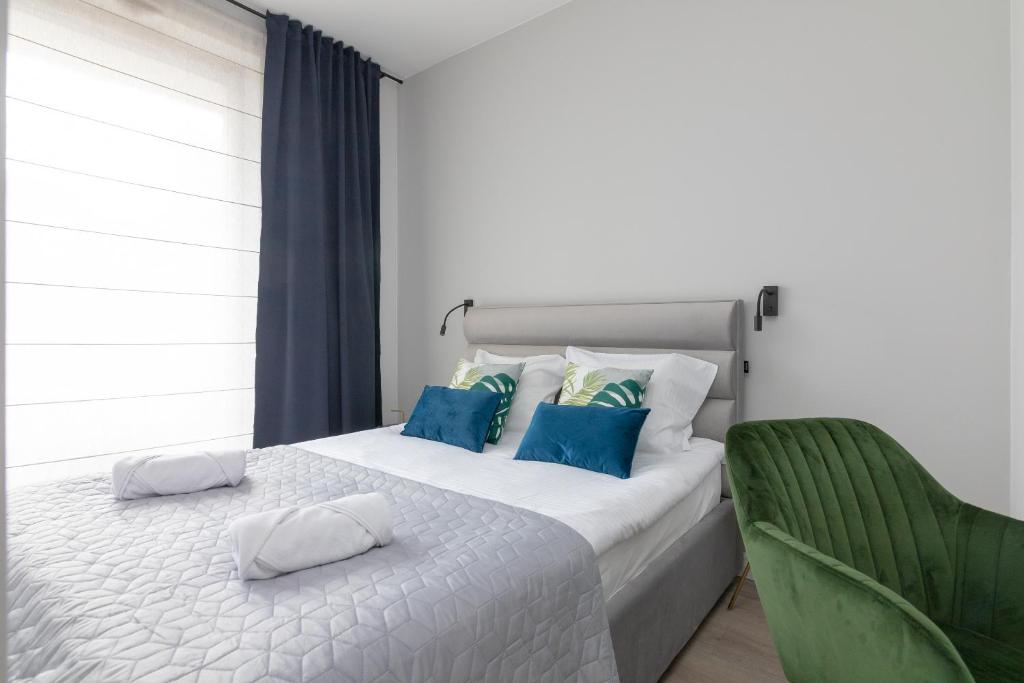 華沙的住宿－Warsaw Spire Stylish Apartament，一张带蓝色枕头和绿色椅子的白色床