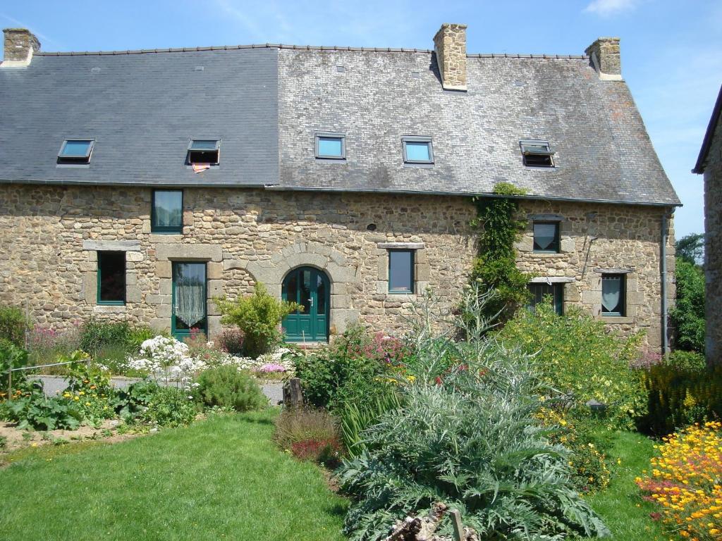 una antigua casa de piedra con un jardín delante de ella en Le Petit Courtoux, en Saint-Germain-en-Coglès