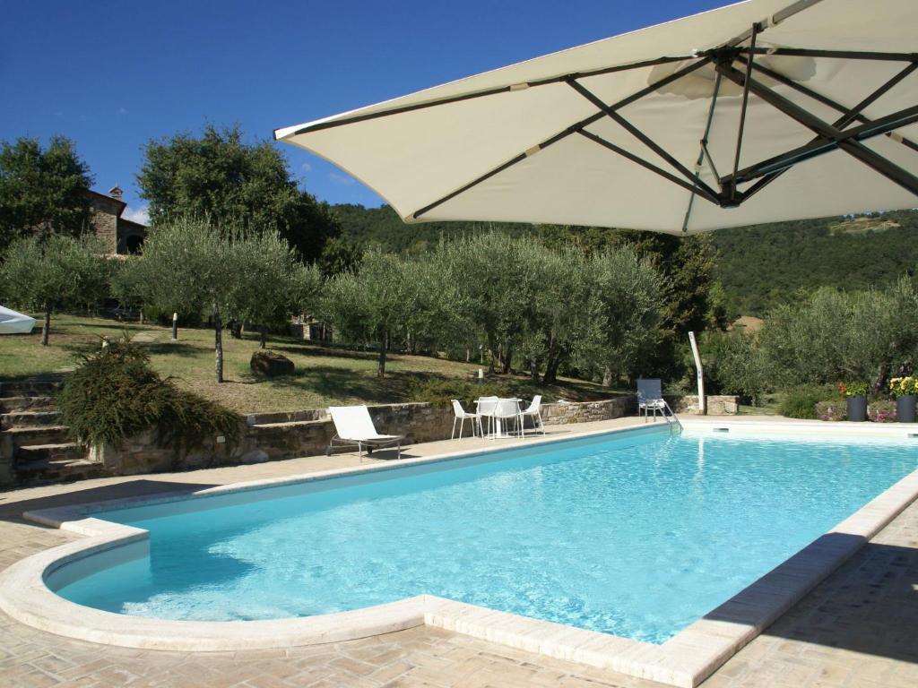 ein Pool mit einem großen weißen Sonnenschirm in der Unterkunft Belvilla by OYO Villa San Donato in Galera