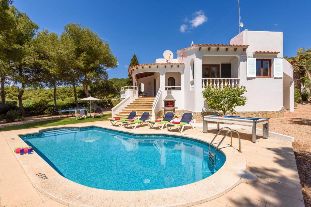 a villa with a swimming pool in front of a house at Villa Amapola by Villa Plus in Santo Tomás