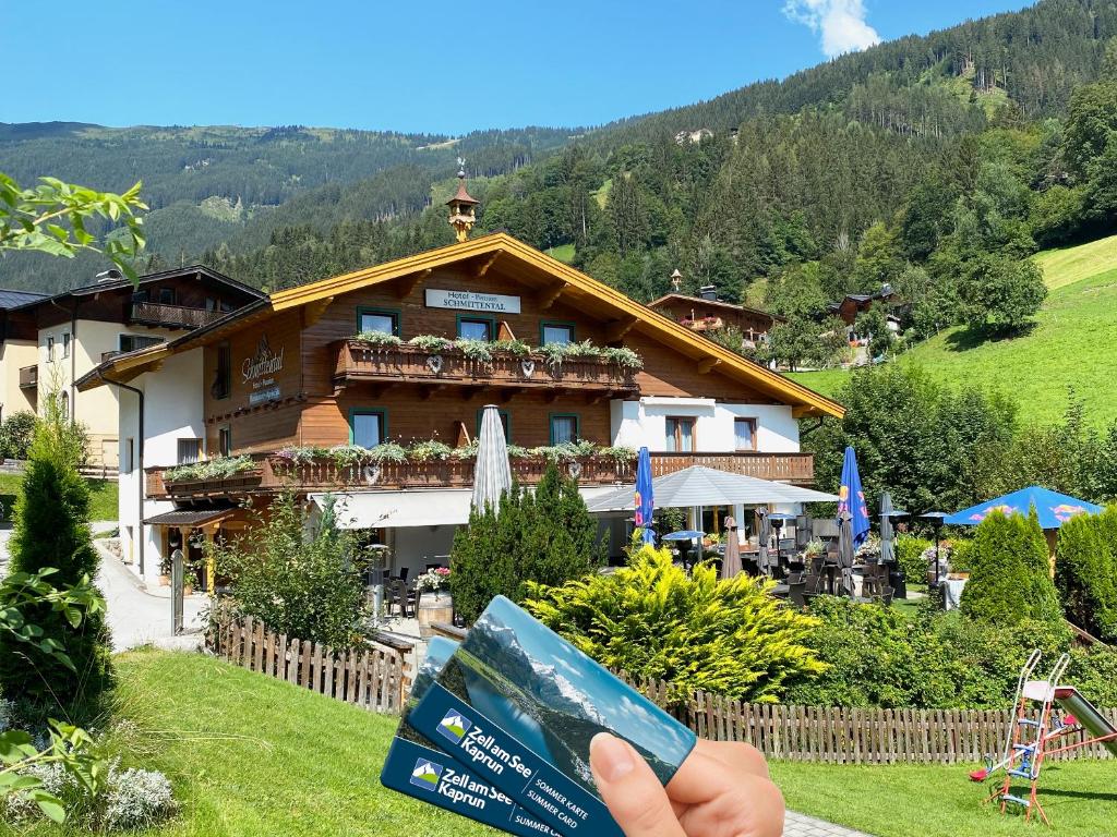 a person holding up a sign in front of a building at Schmittental Pension Self-Check-In in Zell am See
