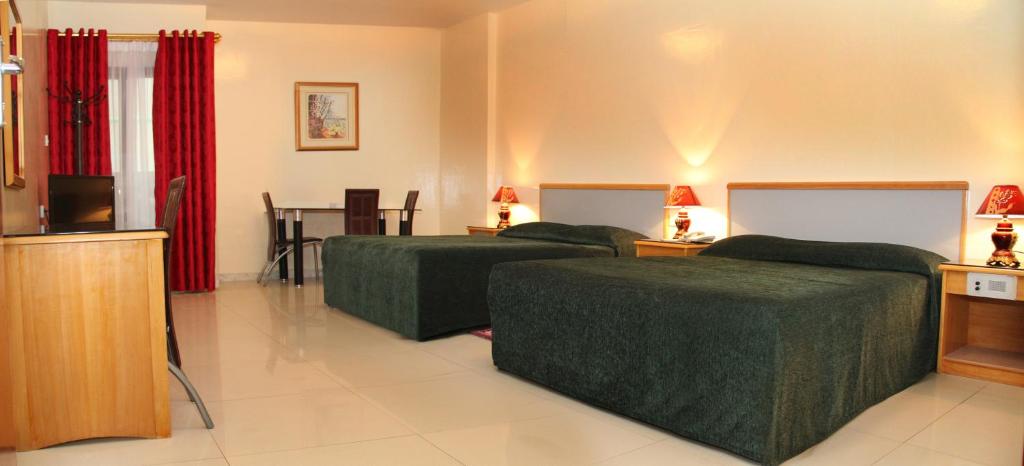 Cette chambre comprend deux lits et une télévision. dans l'établissement Al Buhaira Hotel Apartment, à Charjah