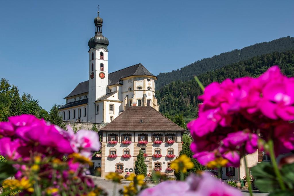 a building with a tower on top of it with pink flowers at Gasthof Löwen in Schruns