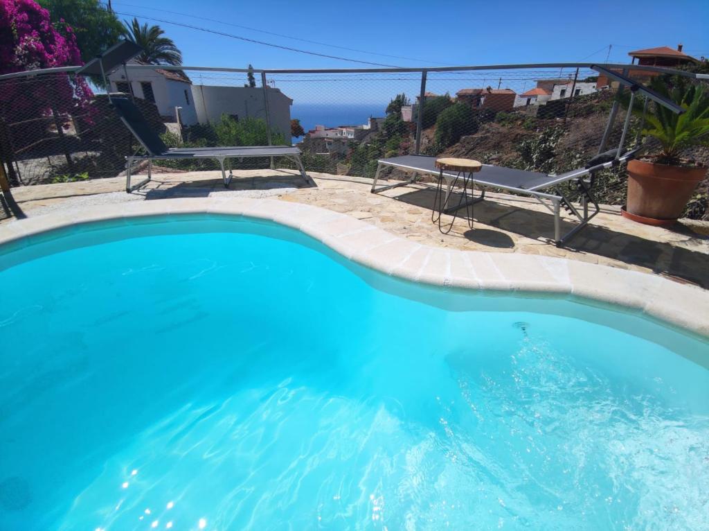 a blue swimming pool with a table and a bench at Romantic Hamlet Cottage with Private Pool La Fragua de Eliseo in Candelaria
