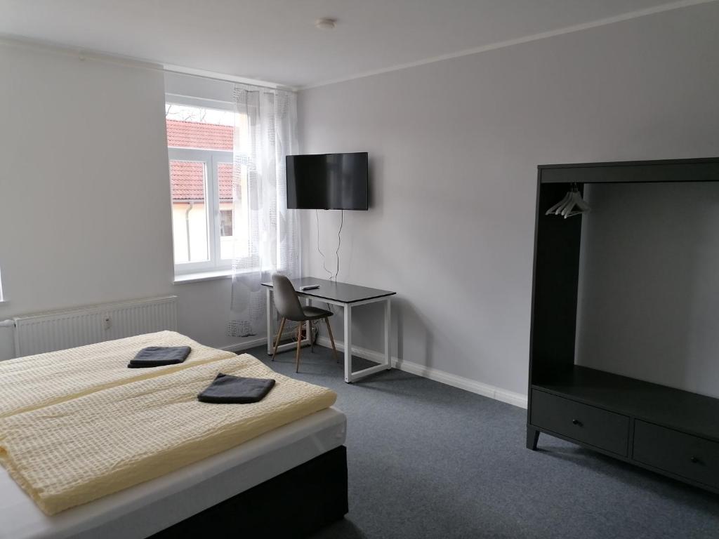 a bedroom with a bed and a desk and a television at Apartment Bona Loca in Aschersleben