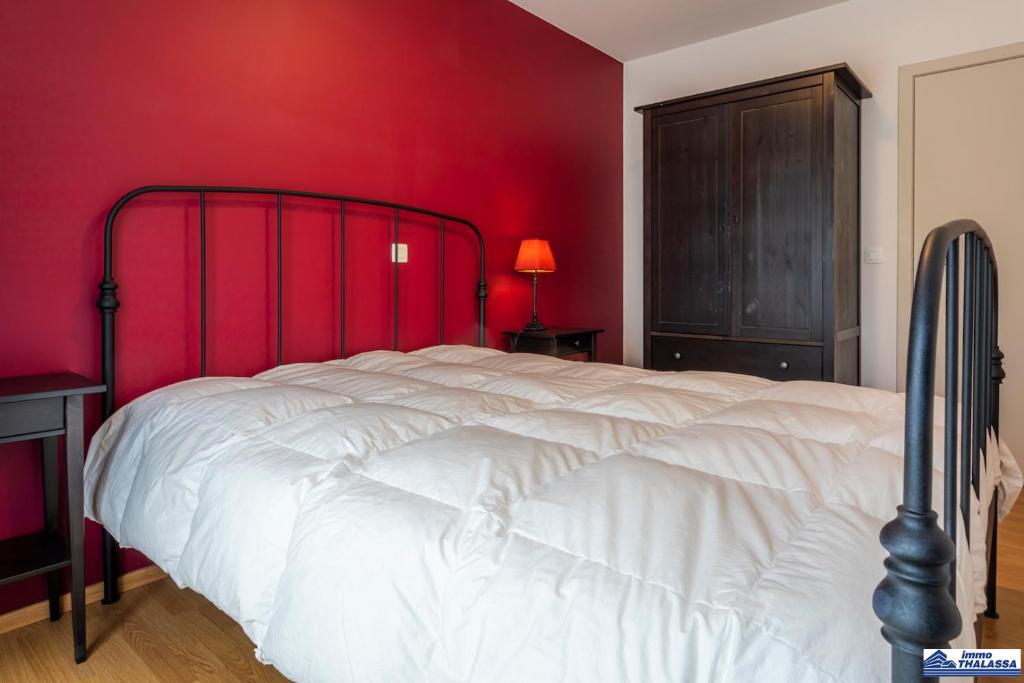 a bedroom with a white bed with red walls at Zeppelin 0102 in Koksijde