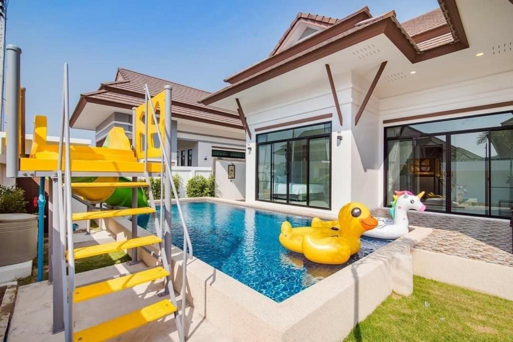 a swimming pool with rubber ducks and a slide at บ้านอิ่มสุข พลูวิลล่า ชะอำ in Hua Hin