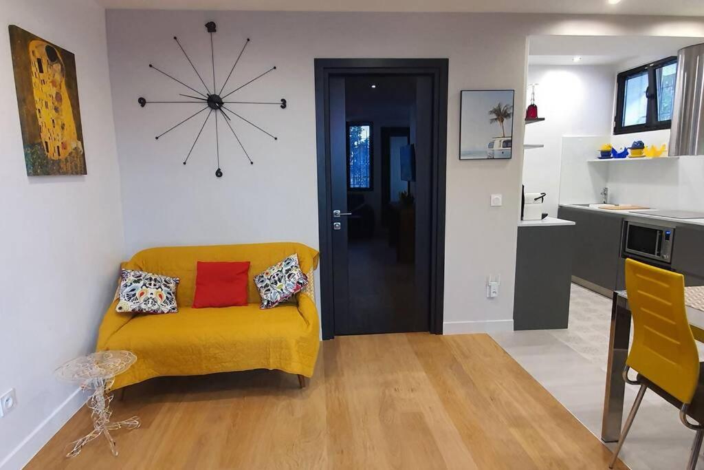 ein Wohnzimmer mit einem gelben Sofa und einer Uhr an der Wand in der Unterkunft Très jolie bas de maison en centre ville, parking, Wi-Fi, Netflix in Cannes