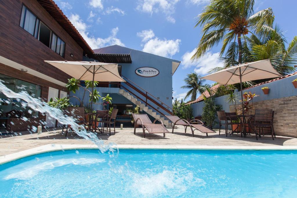 a swimming pool with a fountain in front of a building at Pousada Praia de Porto in Porto De Galinhas