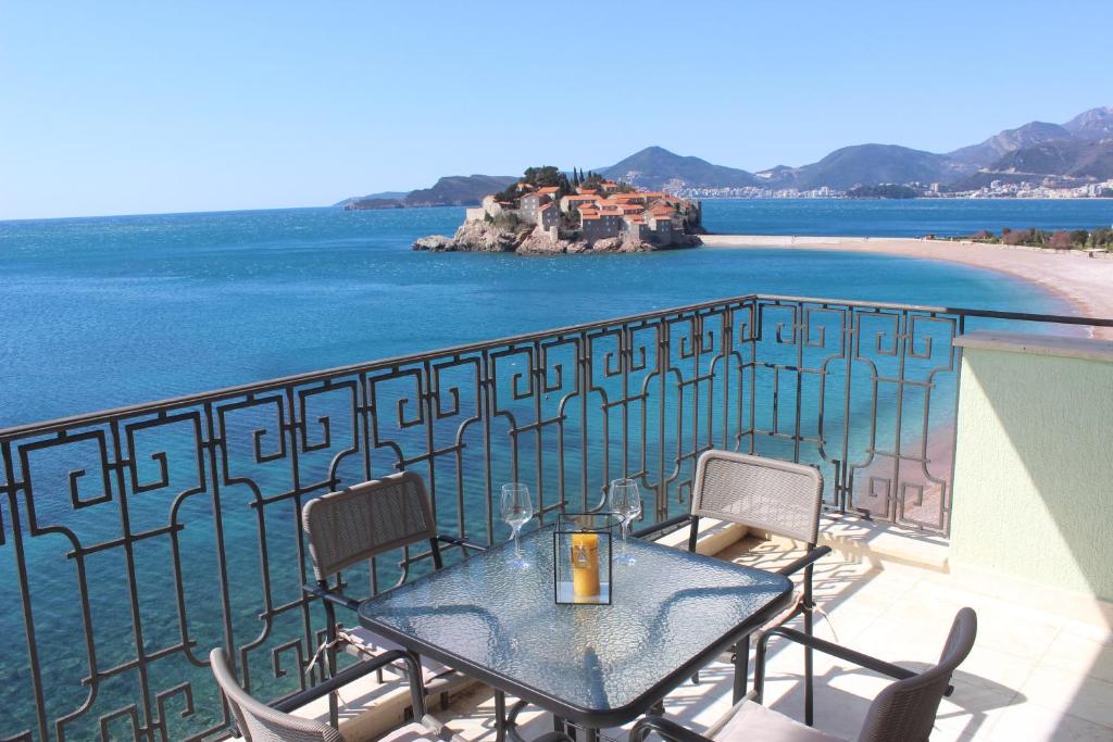 - stół i krzesła na balkonie z widokiem na ocean w obiekcie Sveti Stefan Beach Apartment w Budvie