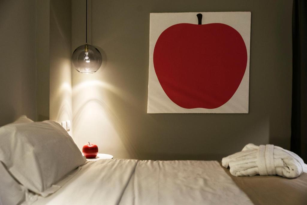 a bed with a red apple painting on the wall at Neko Boutique Hotel in Cagliari