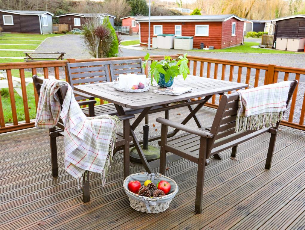 uma mesa de piquenique com 2 cadeiras e uma cesta de frutas em Eirlys em Caernarfon