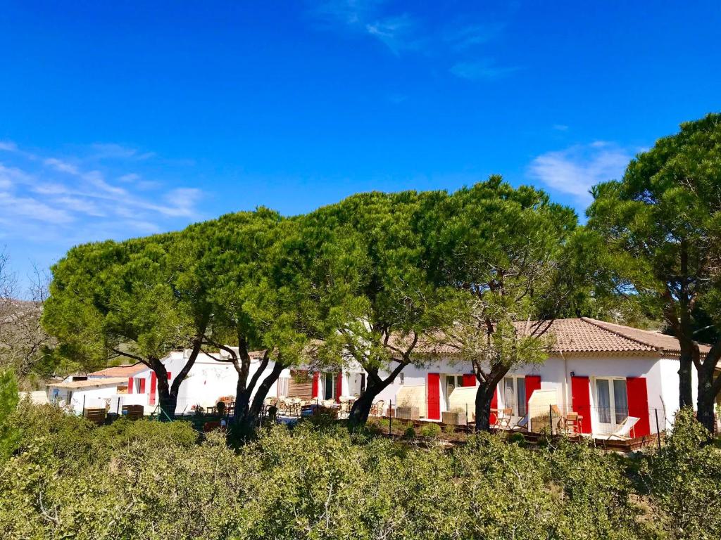 una casa con puertas rojas y árboles en una colina en HôTEL LES VOLETS ROUGES - CASSIS en Cassis