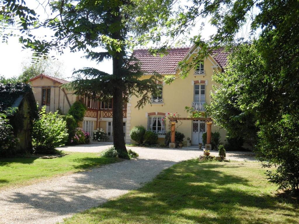 una gran casa amarilla con un árbol en el patio en Domaine la jam, en Marciac