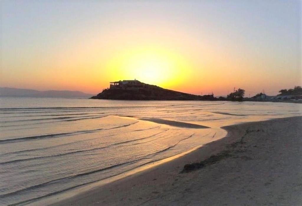 una puesta de sol en una playa con una casa en una isla en Mama's Rooms - Eurostudiosnaxos, en Naxos Chora