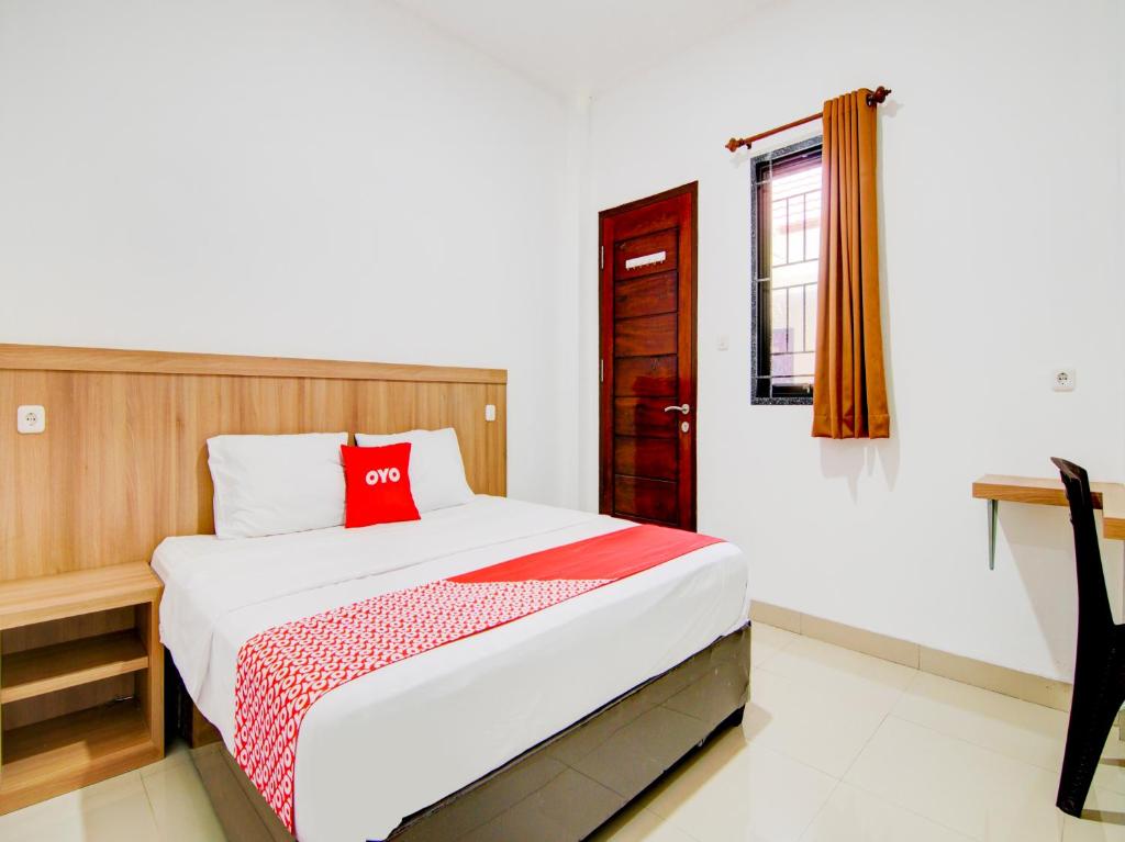 ein Schlafzimmer mit einem Bett mit einem roten Kissen darauf in der Unterkunft OYO 90233 The Shine Residence in Pekanbaru