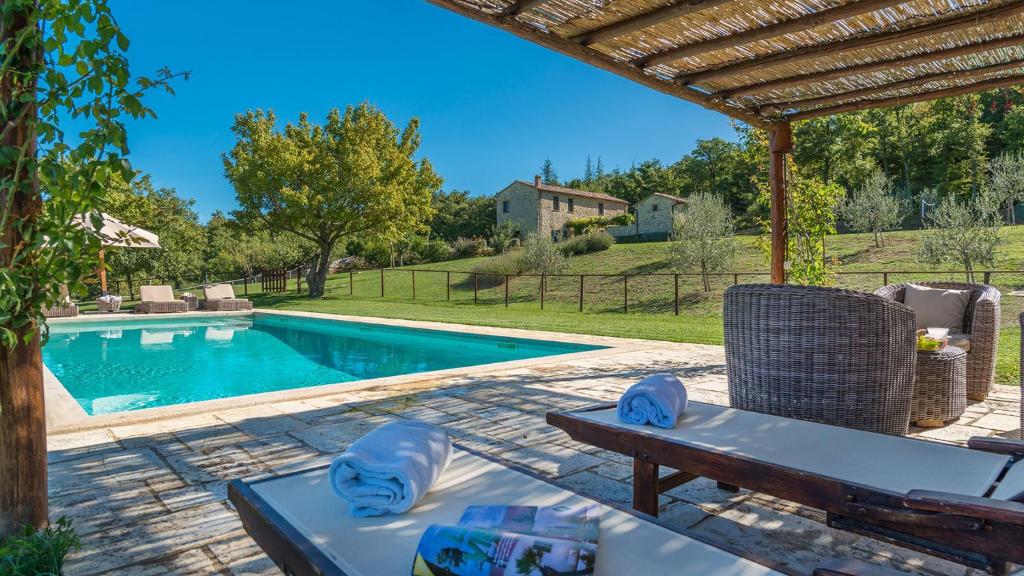un patio con una mesa y una piscina en MUFFATO 6, Emma Villas, en Sarteano