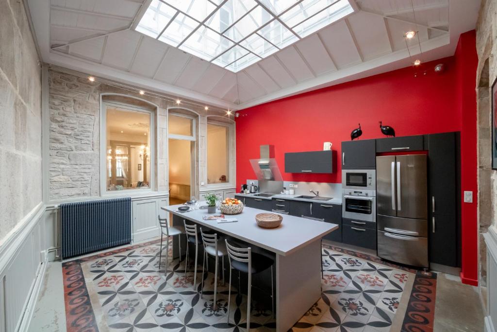 a kitchen with red walls and a kitchen island with chairs at LA PETITE VERRIERE in Beaune