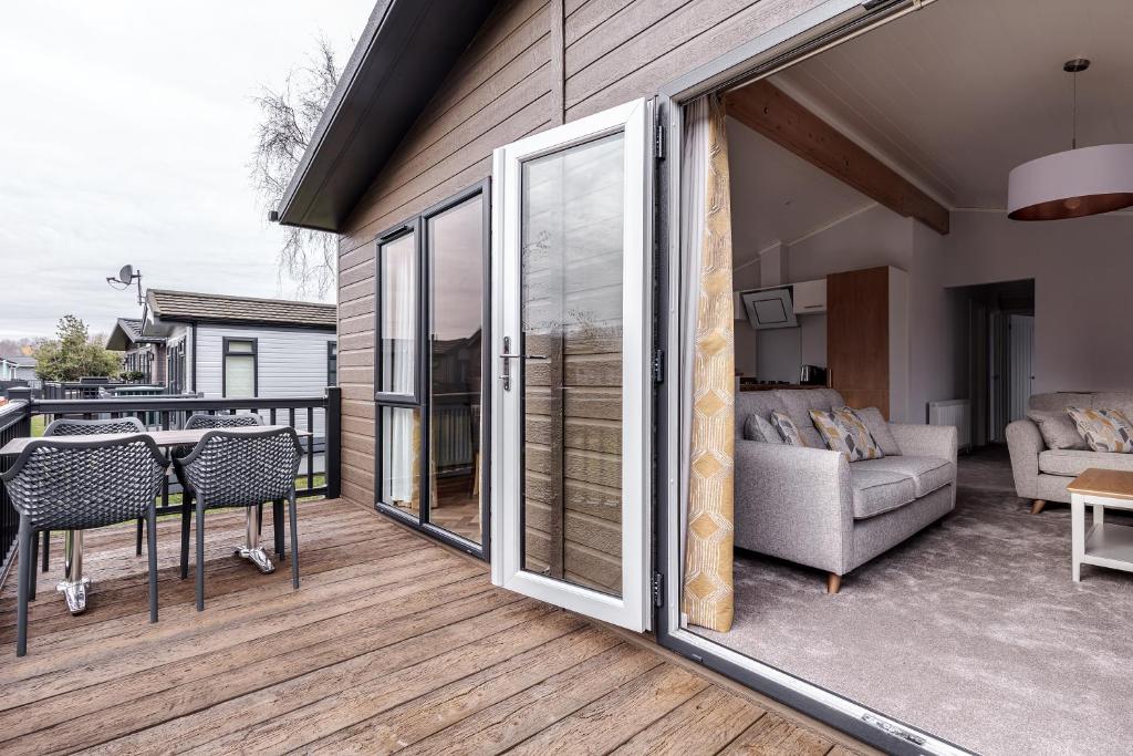 a large sliding glass door on a deck with a couch at Roydon Marina Village Lodges in Roydon