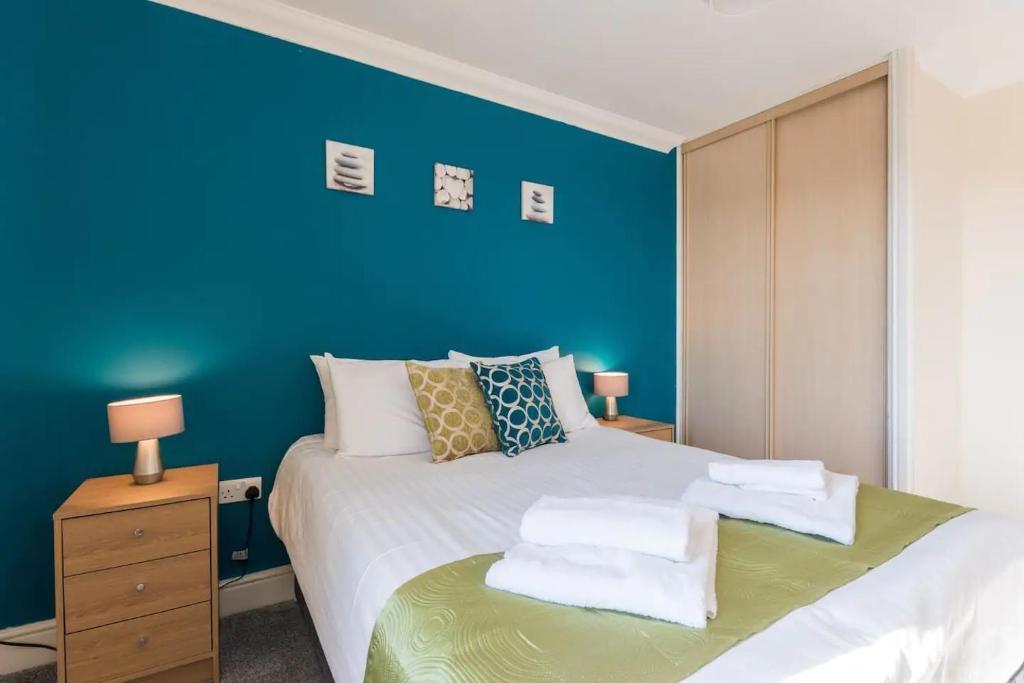 a bedroom with a blue wall and a bed at Godwin Court Apartments in Swindon