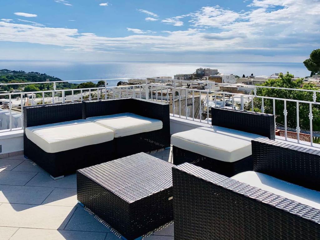a balcony with chairs and tables on a roof at Casa Manì in Anacapri