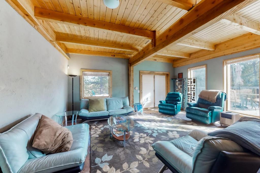 Elle comprend un salon doté d'un mobilier bleu et de plafonds en bois. dans l'établissement Friends & Family Base Camp, à Woodland Park