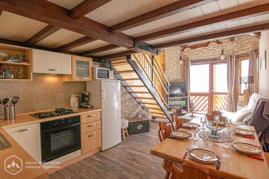 uma cozinha com uma mesa e uma cozinha com uma escada em Résidence Les hauts de Val Cenis em Lanslevillard