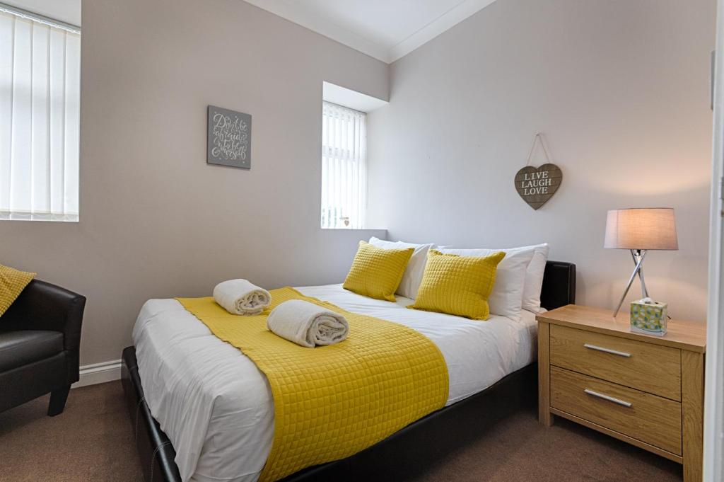 um quarto com uma cama com um cobertor amarelo em Alexandra Lodge em Swansea