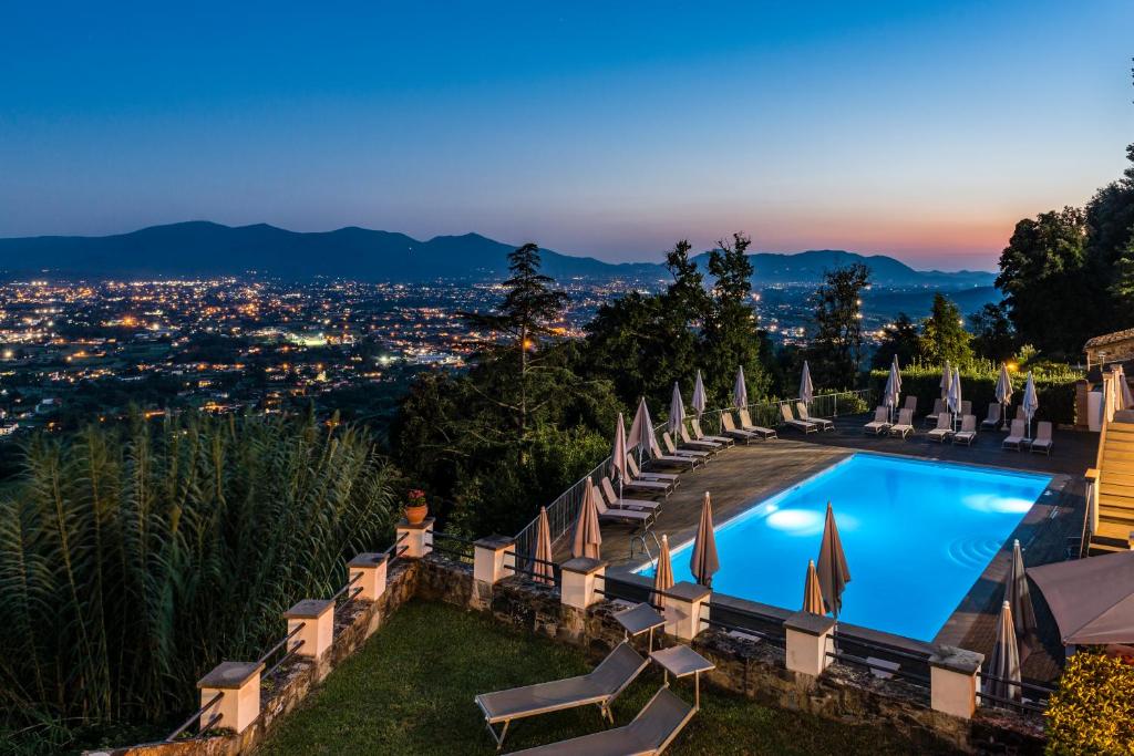 uma vista para uma piscina de resort com cadeiras e uma cidade em Tenuta Guinigi Antico Borgo di Matraia - Exclusive Holidays apartments & Pool em Lucca