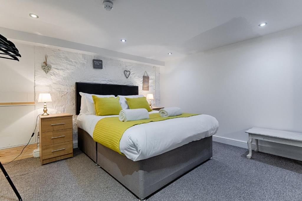 a bedroom with a large bed with yellow pillows at Alexandra Cottage Comfortable Apt near Swansea & M4 in Swansea