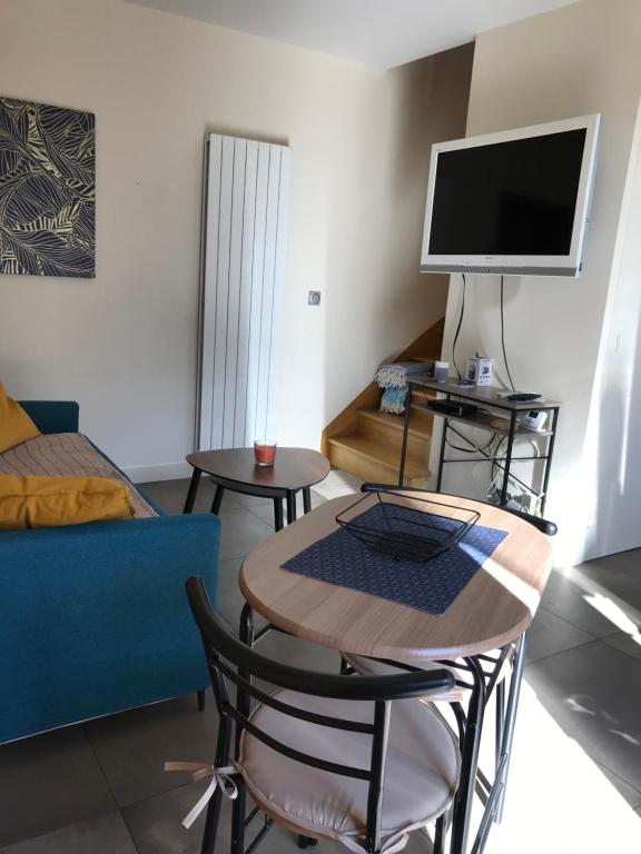 ein Wohnzimmer mit einem Tisch und einem TV in der Unterkunft Studio T1BIS BORD DE PLAGE in Saint-Lunaire